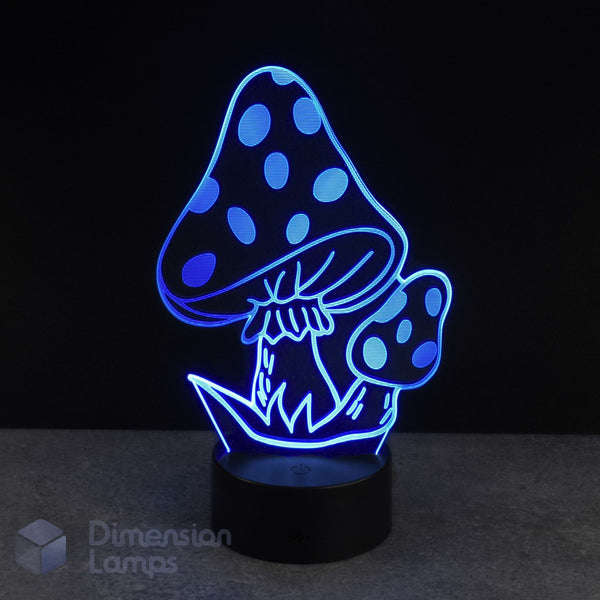 A 3D optical illusion LED night light shaped like two mushrooms, glowing with a bright blue light on a black base against a dark background. A 'Dimension Lamps' watermark is visible in the bottom-left corner.