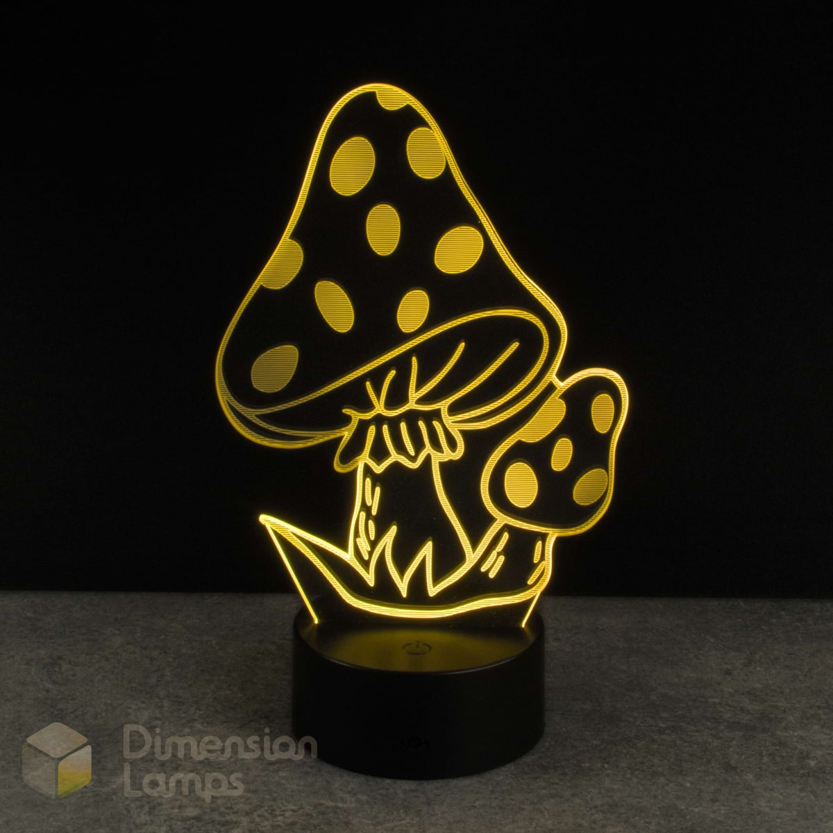 A mushroom-shaped 3D LED night light glowing with warm yellow light, featuring a large spotted mushroom and smaller mushroom on a black cylindrical base, set against a dark background.