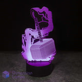 A 3D optical illusion night light featuring Thor's hammer (Mjolnfr) resting on a lightning-bolt base, glowing with purple and pink light against a dark background. A 'Dimension Lamps' logo is visible in the bottom-left corner.