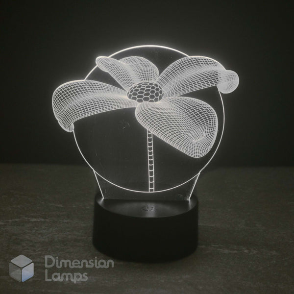 A 3D optical illusion lamp depicting a daisy flower, glowing with white light from a black cylindrical base on a dark grey surface against a black background. Aussie 'Dimension Lamps' watermark is visible in the bottom-left corner.