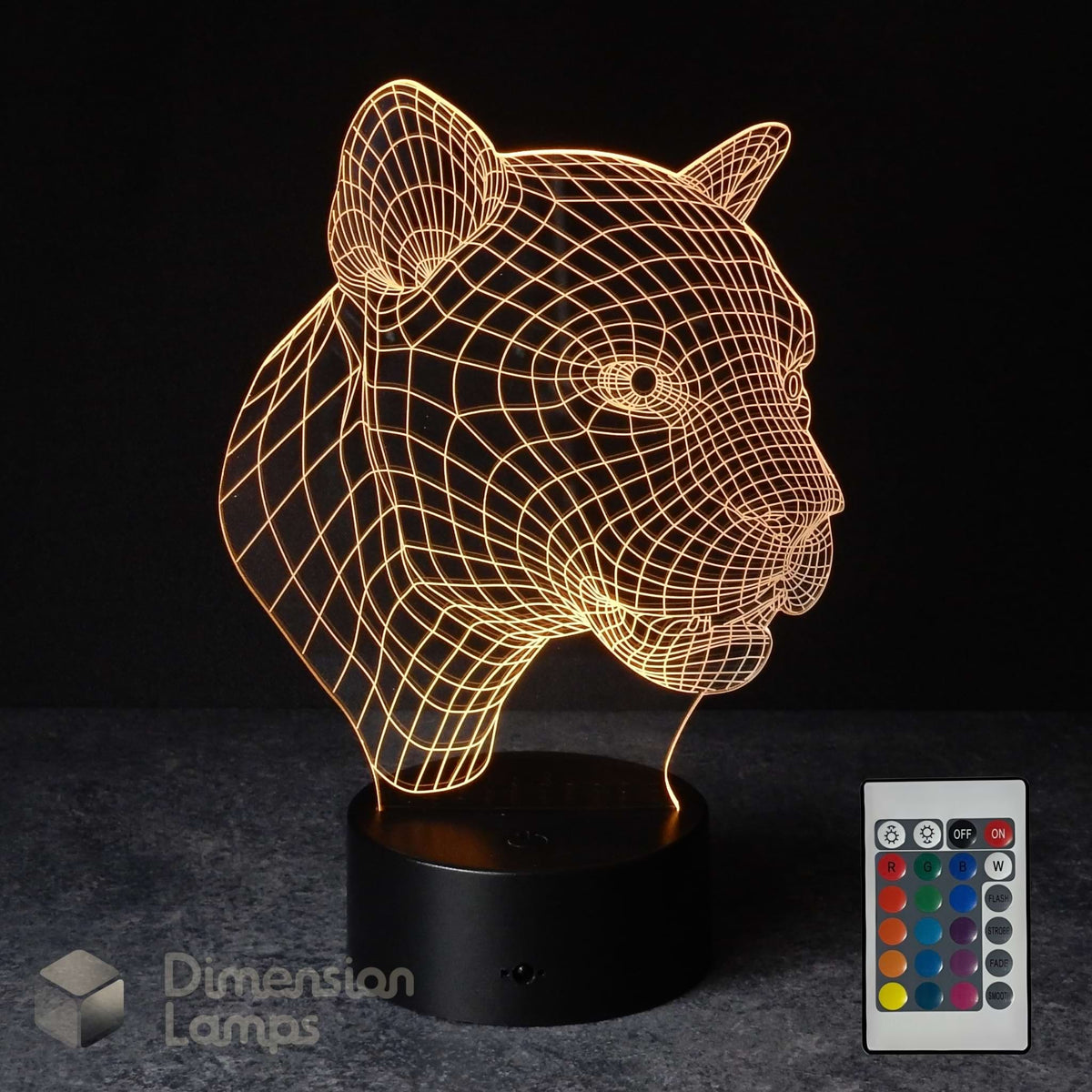 A 3D optical illusion lamp shaped like a panther head, glowing with warm golden light from a black base, shown with a 16 colour remote control on a dark background. The 'Dimension Lamps' logo is visible in the bottom-left corner. Wildlife gift idea. 