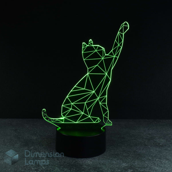 A 3D optical illusion lamp of a cat sitting and pawing, glowing with bright green lines on a black base against a dark background with a Dimension Lamps logo. Perfect as a cat lovers gift. 