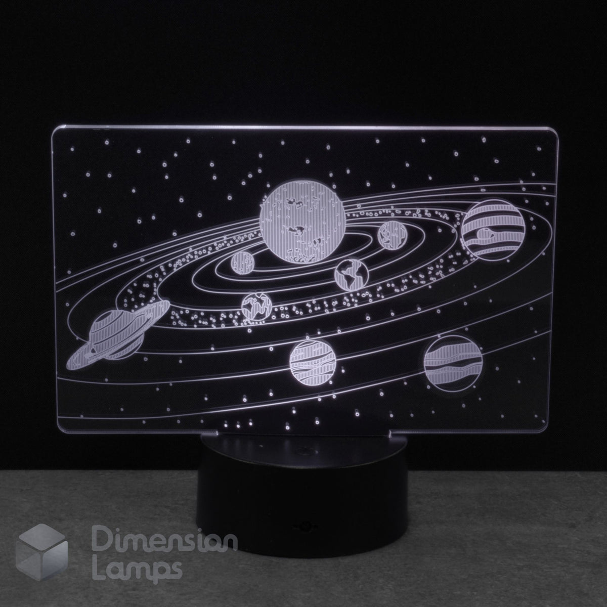 An LED night light with a clear acrylic panel displaying a white solar system design, mounted on a black cylindrical base against a dark background.