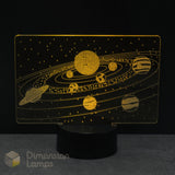 A Dimension Lamps solar system night light featuring a glowing gold acrylic panel with etched planets, stars, and orbital paths on a black base.