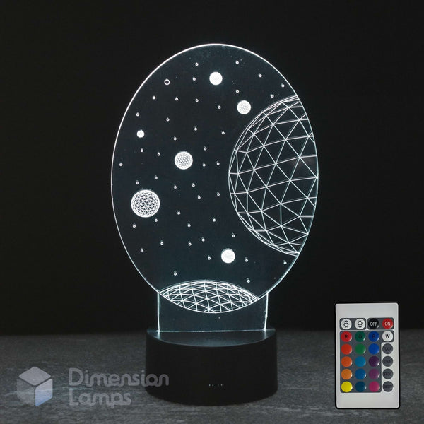 A 3D optical illusion night light shaped like a space scene with planets and stars, shown illuminated on a black base next to its remote control. The brand 'Dimension Lamps' is visible as a watermark in the bottom left corner.