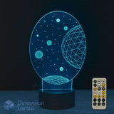 A 3D optical illusion night light shaped like a celestial space scene, glowing with a blue light on a black base, shown with its remote control against a dark background.