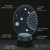 An illuminated 3D acrylic night light with a black base, featuring a celestial design of stars and planets. The image includes text callouts explaining features like 'PRECISION LASER ETCHING', '7 COLOUR MODES', 'CLEAR ACRYLIC DISPLAY', 'STURDY ABS PLASTIC BASE', 'TOUCH-SENSOR OPERATION', and 'DUAL-POWER BATTERY & USB'.