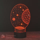 An oval-shaped 3D optical illusion night light by Dimension Lamps, glowing with an orange celestial space design featuring stars and a geometric planet on a black base.