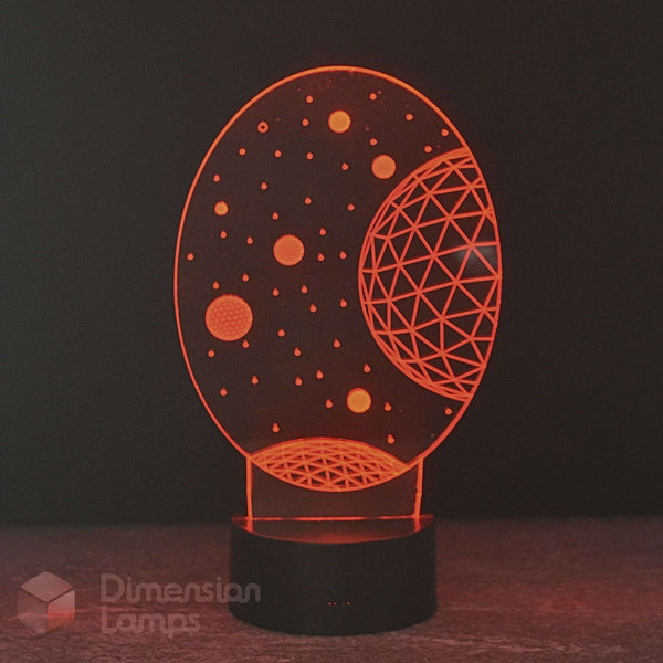An oval-shaped 3D optical illusion night light by Dimension Lamps, glowing with an orange celestial space design featuring stars and a geometric planet on a black base.