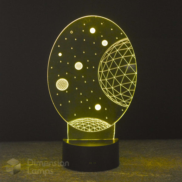 A 3D optical illusion night light by Dimension Lamps featuring a glowing yellow celestial design of planets and stars on a black oval acrylic panel, mounted on a black cylindrical base.