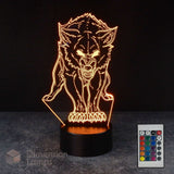 A 3D optical illusion night light shaped like a snarling wolf, glowing with warm orange light from a black base, shown on a dark surface with a small remote control in the lower right corner.
