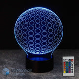 A 3D optical illusion LED lamp shaped like a spherical ball, glowing with blue light, shown on a dark base with a 16 colour remote control in the bottom right corner.