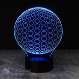 A 3D optical illusion LED lamp shaped like a sphere, glowing with a blue circular pattern on a black base against a dark background.