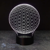 A 3D optical illusion lamp shaped like a glowing white sphere with circular patterns, resting on a black cylindrical base against a dark background.