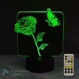 A 3D optical illusion LED night light shaped like a rose with a butterfly, glowing green on a black base, shown with a remote control on a dark background. A 'Dimension Lamps' watermark is visible in the lower-left corner.