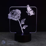 An LED acrylic night light featuring a glowing white line-art rose and butterfly design on a black base, photographed against a dark background.
