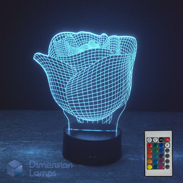 A 3D optical illusion LED night light shaped like a rose, glowing with a bright cyan wireframe effect on a black base, shown with a 16 colour remote control in the bottom right corner against a dark background.