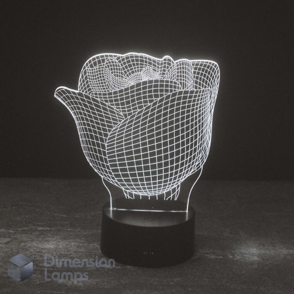 A 3D optical illusion LED lamp shaped like a rose, glowing with white wireframe lines on a black cylindrical base against a dark background. A 'Dimension Lamps' watermark is visible in the bottom-left corner.
