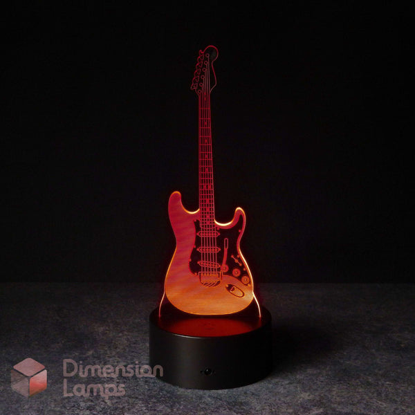 An electric guitar-shaped 3D LED night light glowing with red light, displayed on a black base against a dark background. A 'Dimension Lamps' watermark in the bottom-left corner. Gift for a guitarist.