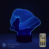 3D LED lamp shaped like a Santa hat with a remote control on a dark background. Christmas themed lamp.