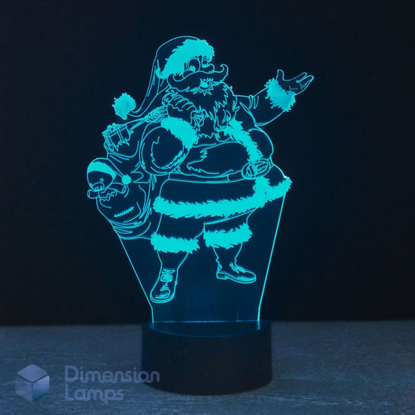 A 3D optical illusion LED night light depicting Santa Claus carrying a sack of gifts, glowing with a bright cyan-blue light on a black base against a dark background.