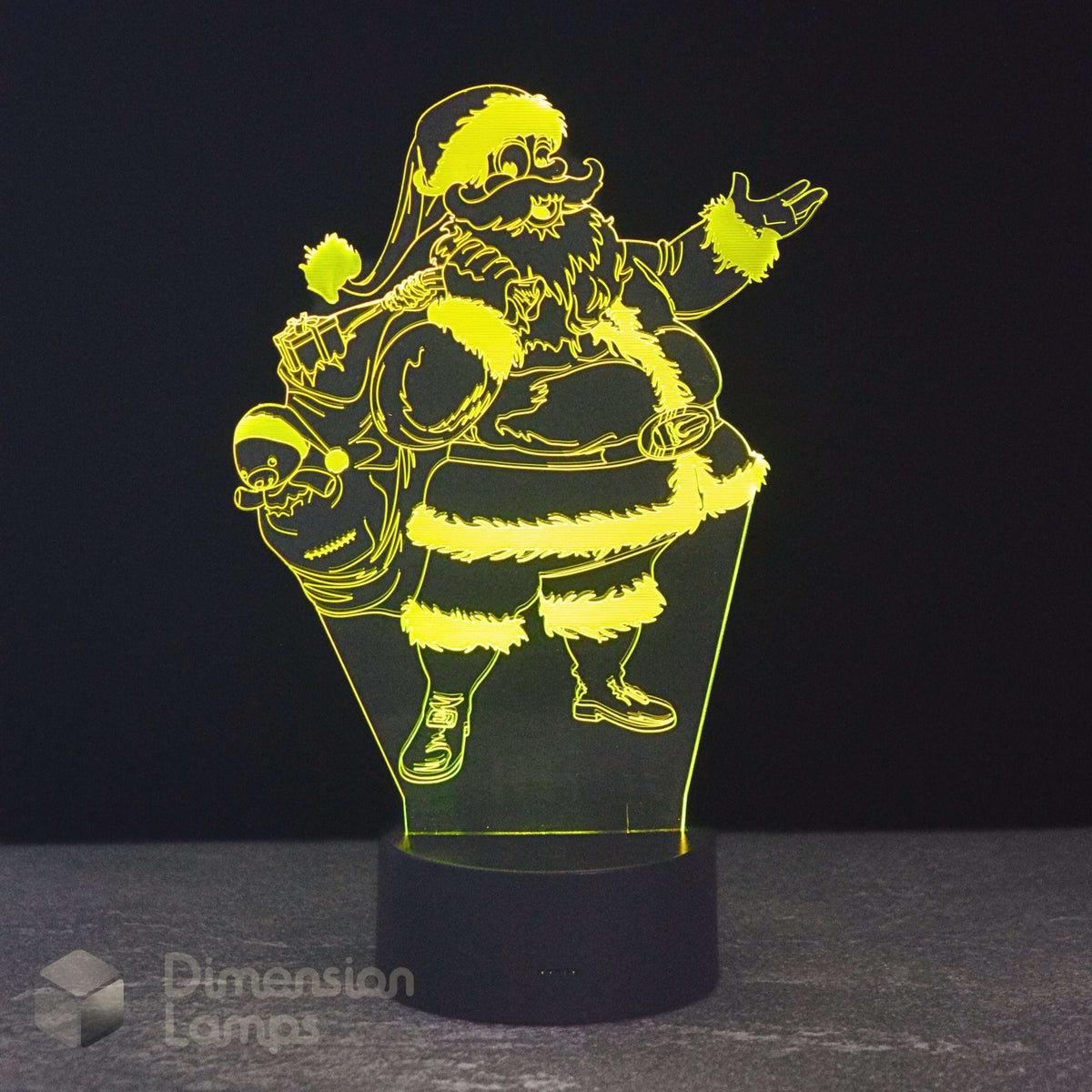A 3D optical illusion LED night light depicting Santa Claus carrying a sack of gifts, glowing with a bright yellow light on a black base against a dark background.