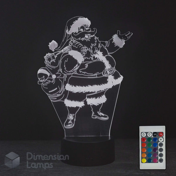 A 3D optical illusion LED night light depicting a cartoon Santa Claus carrying a sack, shown on a black base with a 16 colour remote control in the corner. The brand 'Dimension Lamps' is visible as a watermark.