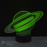A 3D illusion LED night lamp of the planet Saturn, glowing bright green on a black base against a dark background. Gift for kids interested in space.