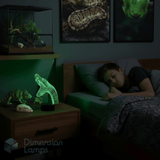 Teen boy sleeping in a dimly lit reptile themed bedroom with a night light shaped like a snake. Gift idea for kids who love snakes. 