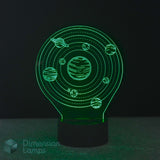 A 3D optical illusion night light featuring a glowing green solar system design with planets and rings on a black base. The brand name 'Dimension Lamps' is visible as a watermark in the bottom-left corner.