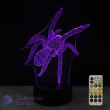 A 3D optical illusion LED night light shaped like a spider, glowing with purple light on a black base, shown with a 7 colour sleep timer remote control against a black background. A 'Dimension Lamps' logo is visible in the bottom-left corner.
