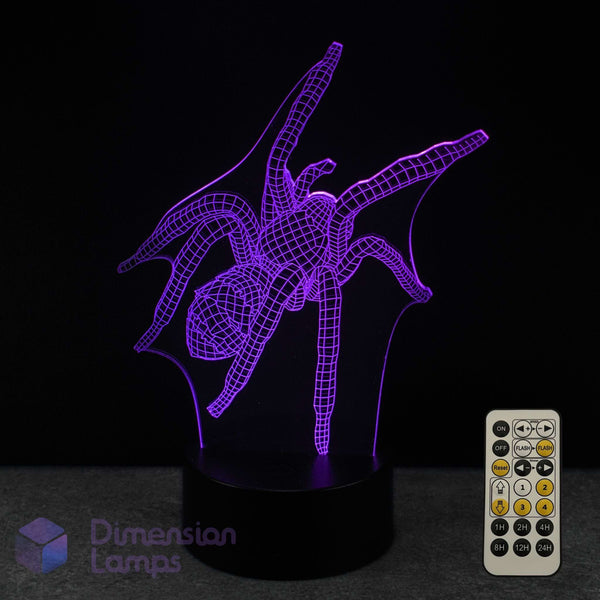 A 3D optical illusion LED night light shaped like a spider, glowing with purple light on a black base, shown with a 7 colour sleep timer remote control against a black background. A 'Dimension Lamps' logo is visible in the bottom-left corner.