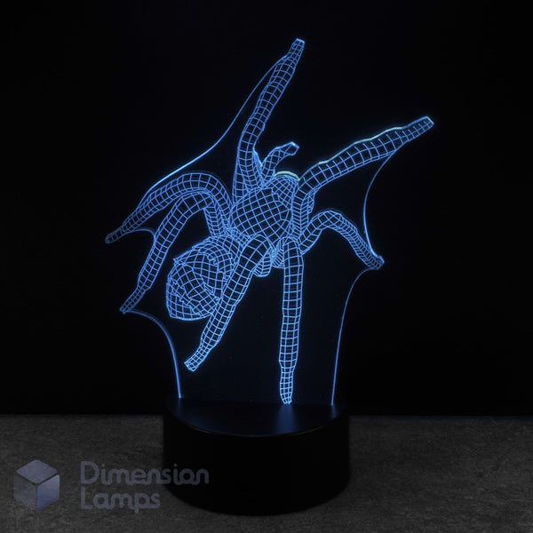 A 3D optical illusion LED night light shaped like a spider, glowing with a cyan wireframe effect on a black base against a dark background. A 'Dimension Lamps' watermark is visible in the bottom-left corner. Spider novelty light.