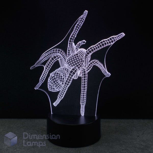 A 3D optical illusion LED night light shaped like a spider, glowing with a white wireframe design on a black base against a dark background. A 'Dimension Lamps' watermark is visible in the bottom-left corner. Spider gift for teens. 