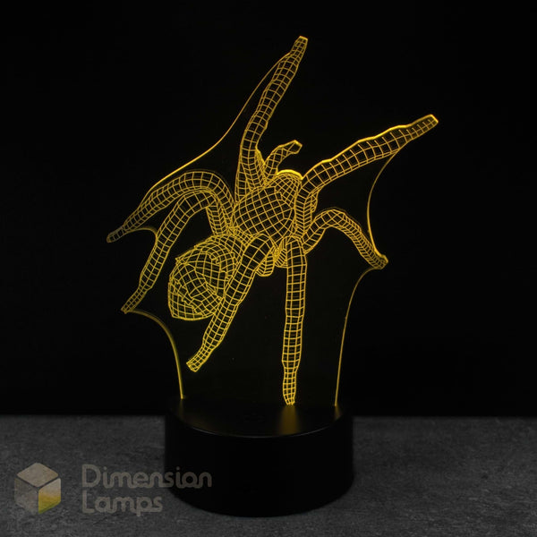 A 3D optical illusion LED lamp depicting a spider in a wireframe grid pattern, glowing yellow against a black background on a dark base. Spider gift for teens. 