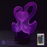 A 3D optical illusion LED night light with two interlocking hearts, glowing purple on a black base, with its 16-colour remote Dimension Lamps logo.