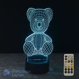 A 3D LED light of a teddy bear, glowing cyan wireframe on a black base, with a 7 colour remote control on a dark background and a Dimension Lamps logo