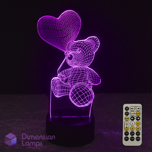 3D LED lamp shaped like a teddy bear with a heart balloon, accompanied by a remote control, on a dark background.