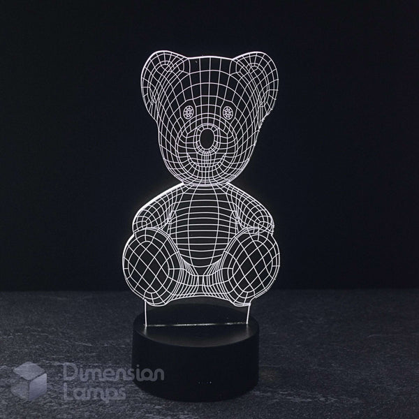 A 3D optical illusion LED night light of a teddy bear, featuring a glowing white wireframe design on a black base, set against a dark background.