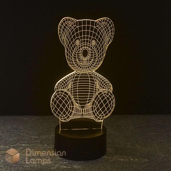 A teddy bear 3D optical illusion LED night light on a black base against a dark background. warm golden light, gift idea for kids that love teddies.
