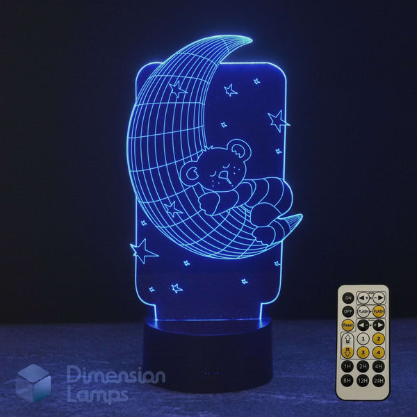 A 3D lamp of a teddy bear sleeping on a crescent moon, glowing blue against a dark background, a 7 colour remote control and Dimension Lamps logo.