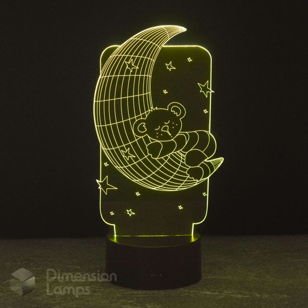 A 3D lamp by Dimension Lamps featuring a teddy bear sleeping on a crescent moon under stars, glowing warm yellow light against a dark background.