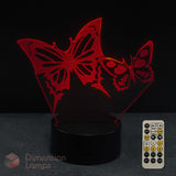 Red laser-cut butterfly 3D LED night light on a black base with a remote control, shown against a dark background and 'Dimension Lamps' watermark.