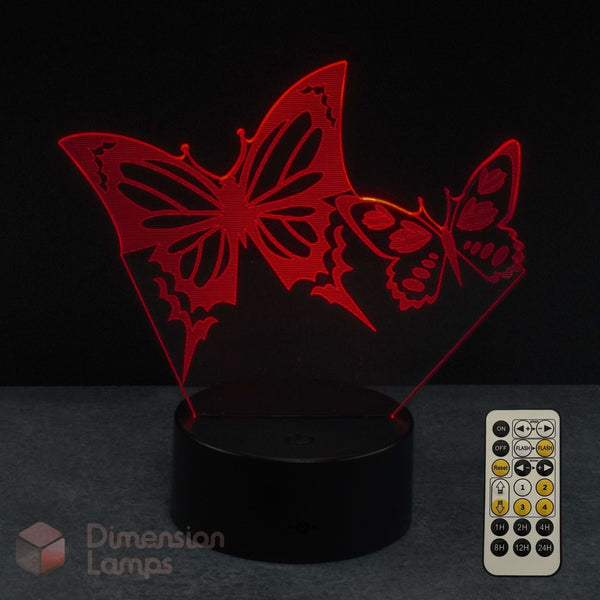 Red laser-cut butterfly 3D LED night light on a black base with a remote control, shown against a dark background and 'Dimension Lamps' watermark.
