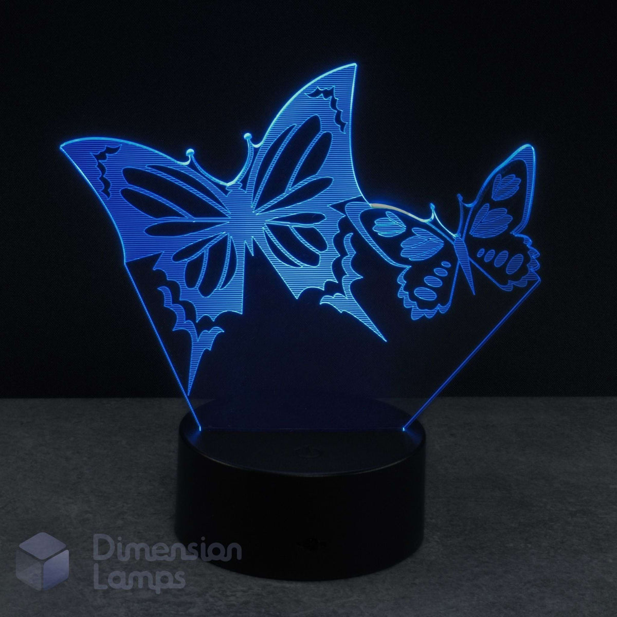 A 3D optical illusion LED night light featuring two glowing cyan butterfly silhouettes on a black base, against a dark background. Girls gift idea.
