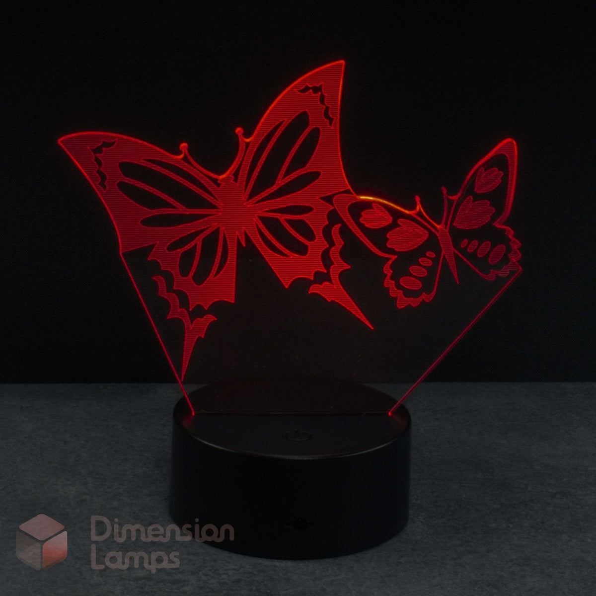 A 3D laser-cut acrylic night light featuring two glowing red butterflies on a black base against a dark background. 