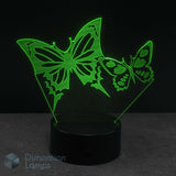 A 3D optical illusion night light featuring two glowing green butterfly shapes on a black base.
