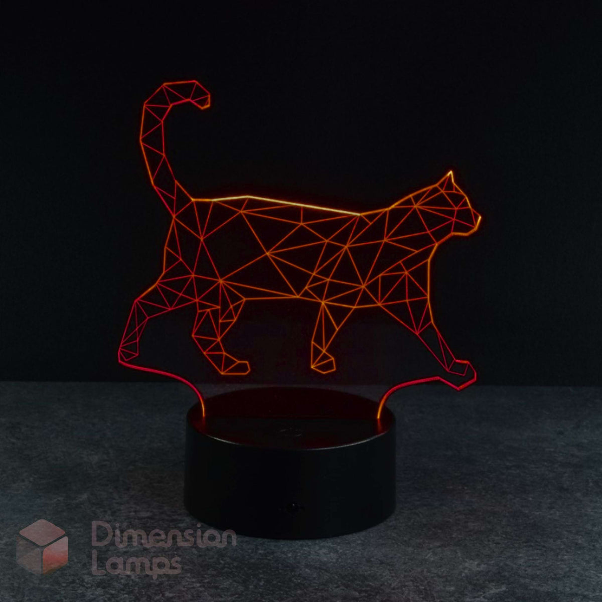 A 3D optical illusion LED night light shaped like a walking cat, glowing with a red light from a black cylindrical base on a dark grey surface against a black background. Cat lovers gift idea.