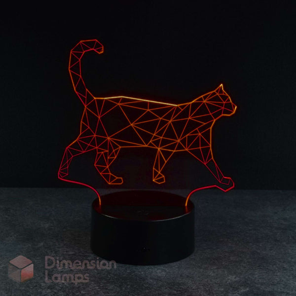 A 3D optical illusion LED night light shaped like a walking cat, glowing with a red light from a black cylindrical base on a dark grey surface against a black background. Cat lovers gift idea.