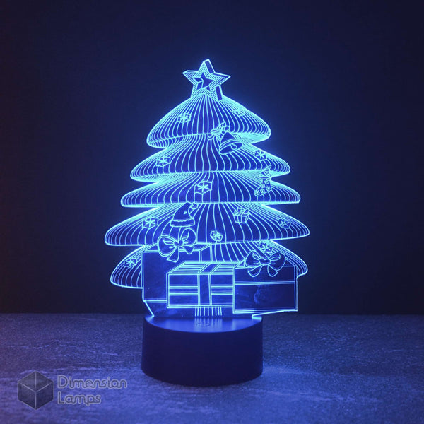 Nightlight shaped like a Christmas tree with presents underneath, illuminated in a calming blue. This 3D lamp adds a festive touch to any room during the Christmas season.
